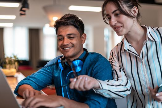 Multiethnic business people man with a female colleague working together on tablet and laptop computer in relaxation area of modern startup office. High-quality photo