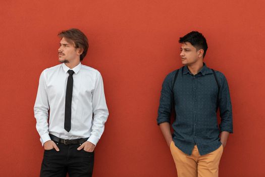 Casual multiethnic startup businessmen during a break from work in front of the red wall outside. High-quality photo