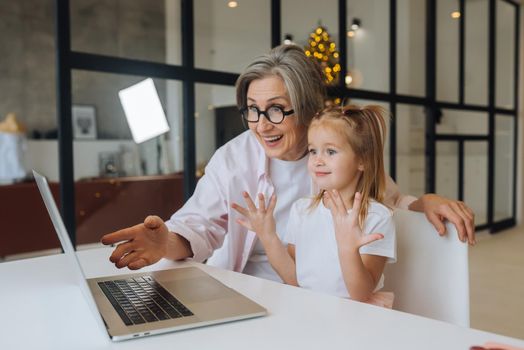 Child and granny looking at the camera with laptop at home