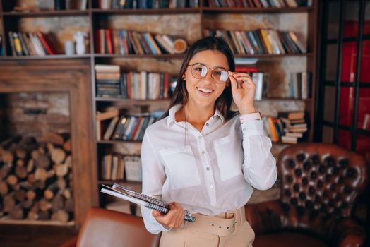 Young woman with documents on the background of a bookshelf