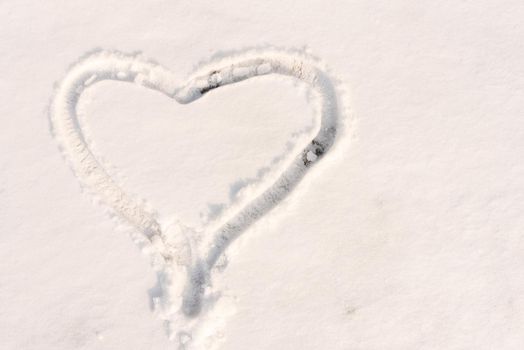 The symbol of the heart, painted on the fresh white snow with copy space.