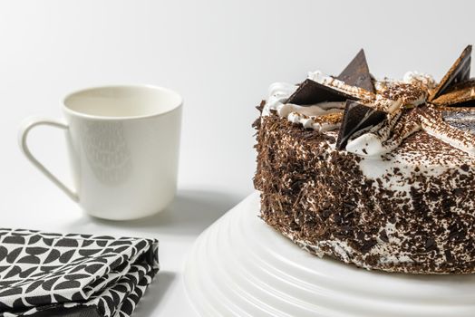 close up view on sweet cake with a cup of tea or coffee and kitchen towel on a light background.