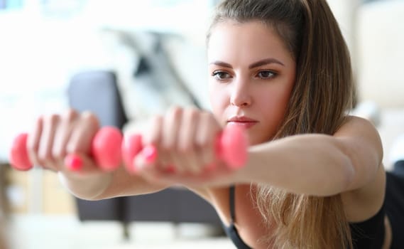 Portrait of young lying woman with dumbbells. Fitness and sport concept