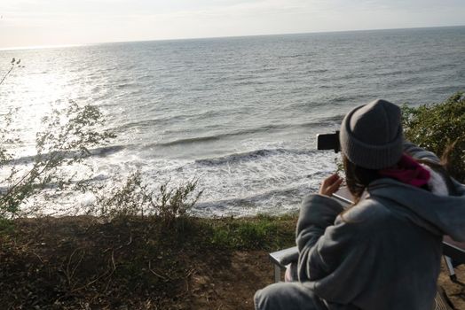 Woman takes a photo on a smartphone of the seascape