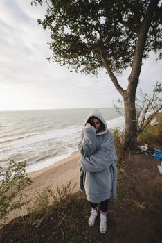 Woman on cold autumn seashore posing at camera