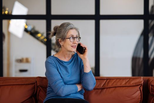Image of senior woman talking on smartphone at home