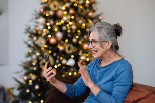 Happy smiley face senior elderly woman using smartphone video call conference camera and talking with family.Video chat social distancing.