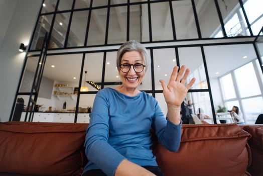 Middle Aged Woman Smiles and Waves to the Camera