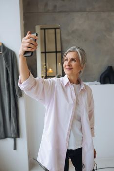 Close up photo of cheerful confident excited dreamy elderly female taking making self portrait
