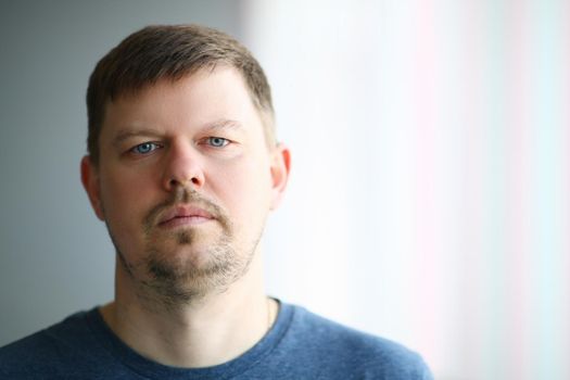 Portrait of young sad man in front of window. Depressive stress state in men concept