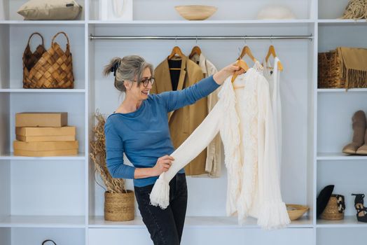 Elderly woman during chooses white sweater