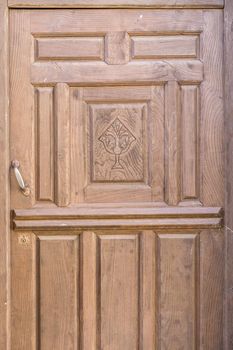 Religious decorated old wooden door, brown painted with chalice