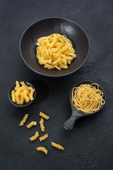 Raw pasta, isolated on a black background, top view.