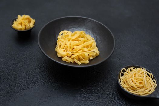 Raw pasta, isolated on a black background, top view.