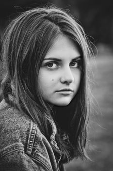 black and white profile portrait of a teenage girl with long hair on a nature background