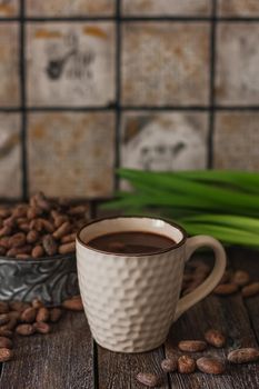 Hot chocolate drink in a white cup, chocolate cubes, cinnamon sticks and coffee bean on the dark wooden background.