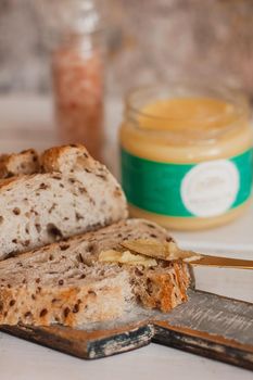 Ghee butter in glass jar and sliced bread on table. Healthy eating, breakfast.