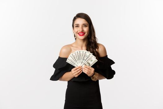 Beauty and shopping concept. Fashionable woman with red lips, showing dollars and smiling, standing over white background with money.