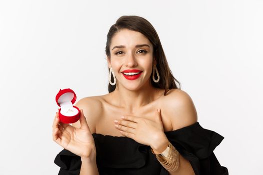 Close-up of happy woman showing her engagement ring, receive marriage proposal, saying yes, standing over white background.
