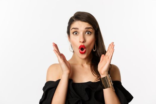 Fashion and beauty concept. Close-up of excited woman with makeup and red lipstick on, looking surprised and glad, standing over white background.