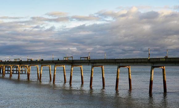 Deal Pier with clouds in the sky and sun on the piles.