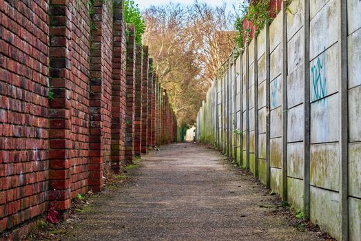 A brick wall on one side and concrete panels on the other. Looking down an urban alley.