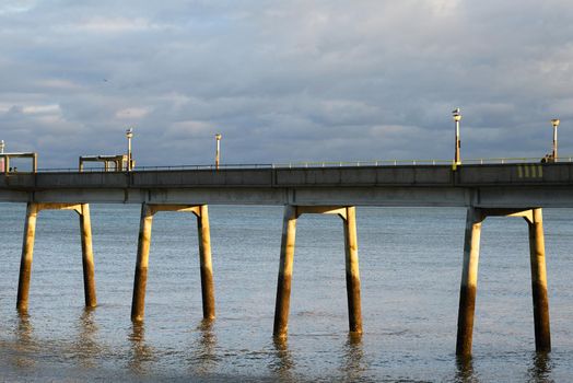 Early evening sun illuminates the piles of Deal Pier in Kent.