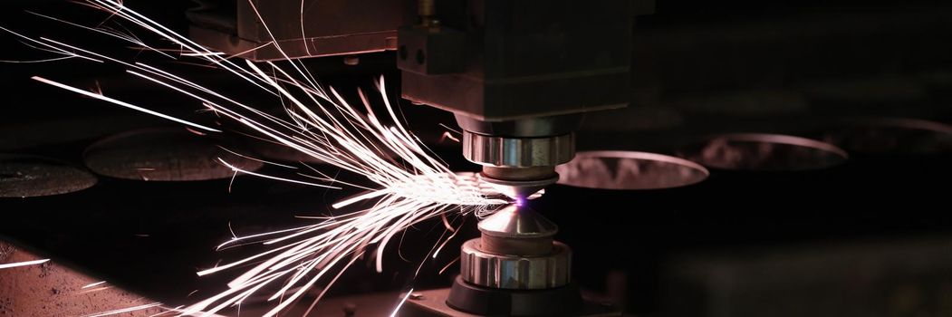 Industrial Laser cutting processing manufacture technology of flat sheet metal steel material with sparks. Electric sparksof metal against dark background.