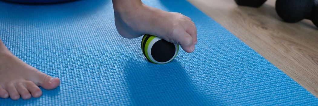 Child foot rests on small gymnastic ball to massage feet. Massage ball games and exercises