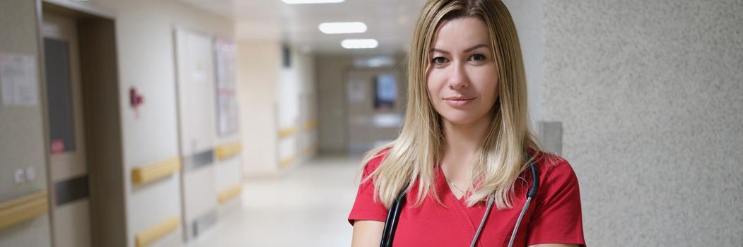 Portrait of young beautiful female doctor in red uniform and stethoscope. General doctor consultation concept