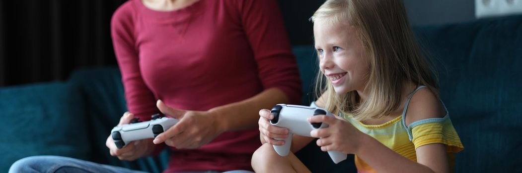 Mom and daughter play online games on console. Parents dissatisfaction with children hobby for computer games concept