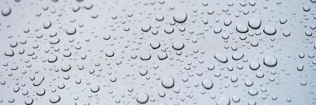 Raindrops on glass against gray sky. Rainy season concept