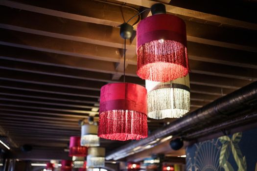 Chandeliers illuminating spacious contemporary pub with old wooden beamed ceiling.