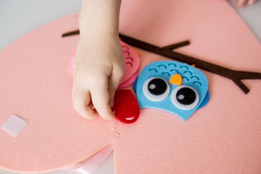 A blogger girl makes a felt craft for Valentine's Day in the shape of a heart. The concept of children's creativity and handmade.