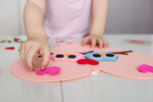 A blogger girl makes a felt craft for Valentine's Day in the shape of a heart. The concept of children's creativity and handmade.