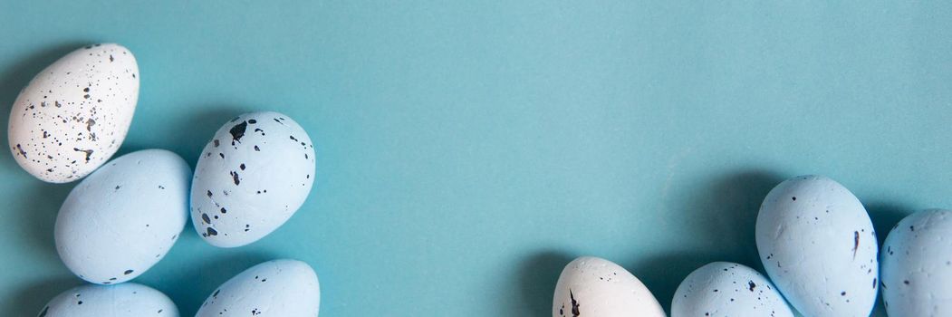 Easter background. Blue and white painted quail eggs on a blue background, decorated with cotton. Happy Easter holiday.