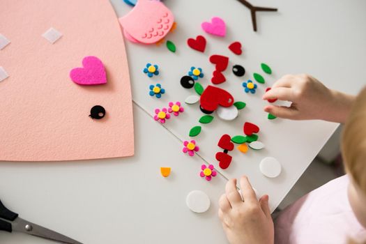 A blogger girl makes a felt craft for Valentine's Day in the shape of a heart. The concept of children's creativity and handmade.