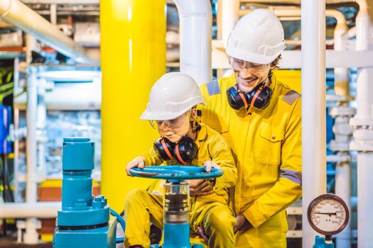 Young man and a little boy are both in a yellow work uniform, glasses, and helmet in an industrial environment, oil Platform or liquefied gas plant.