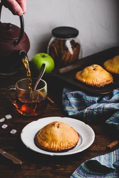 Homemade apple mini pie on white plate with cup of black tea