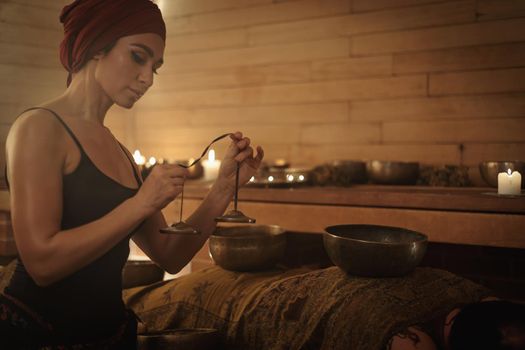 A woman performs a Tibetan ritual with sound bells. The concept of therapy.