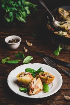 Baked shells pasta stuffed with ground beef, spinach and cheese on white plate