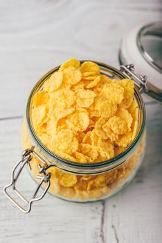 Corn flakes in a glass jar on wooden surface