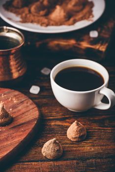 Homemade chocolate truffles coated in cocoa powder with black coffee