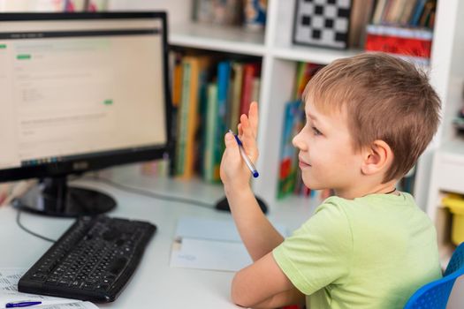 Little young school boy working at home with a laptop and class notes studying in a virtual class. Distance education and learning, e-learning, online learning concept during quarantine