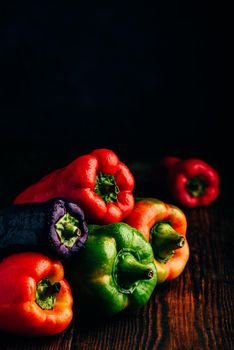 Multicolored fresh bell peppers over wooden background