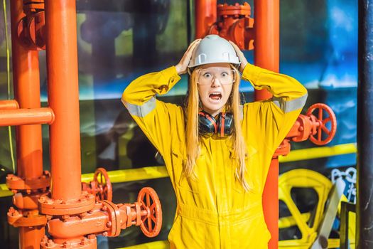 Young woman in a yellow work uniform, glasses and helmet in industrial environment,oil Platform or liquefied gas plant.