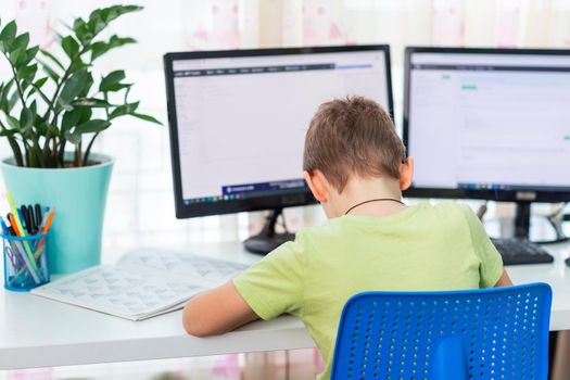 Little young school boy working at home with a laptop and class notes studying in a virtual class. Distance education and learning, e-learning, online learning concept during quarantine