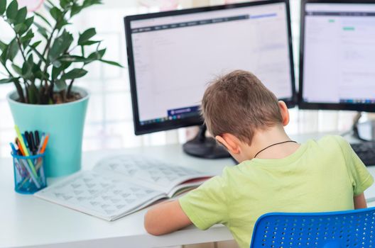 Little young school boy working at home with a laptop and class notes studying in a virtual class. Distance education and learning, e-learning, online learning concept during quarantine