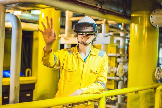 Young woman in a yellow work uniform, glasses and helmet uses virtual reality glasses in industrial environment,oil Platform or liquefied gas plant.