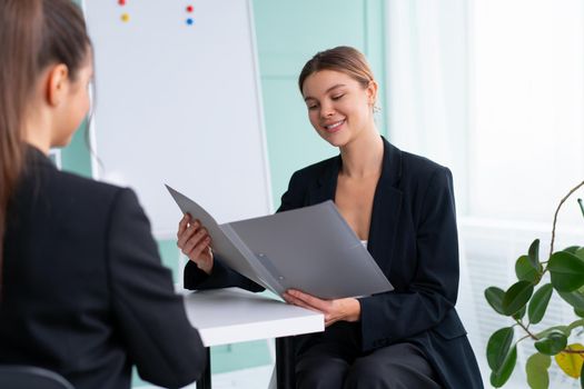 Business meeting. Young blonde woman holding contract while sitting in front of consultant during corporate meeting. Boss discuss ideas with business partner. handshaking deal
